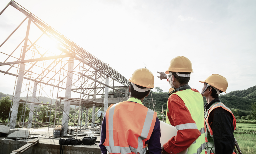A construction team is gathered at an active job site, using tablets to access project files and sensitive project information. They are collaborating in real-time, managing project data and documents efficiently to meet project deadlines and enhance productivity.